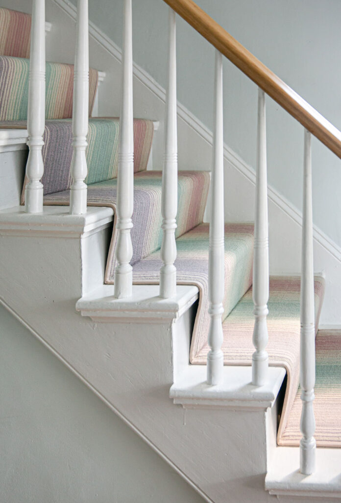 A soft pastel rainbow carpet runner on the stairs of a sunlit cottage in Bridgefield ct