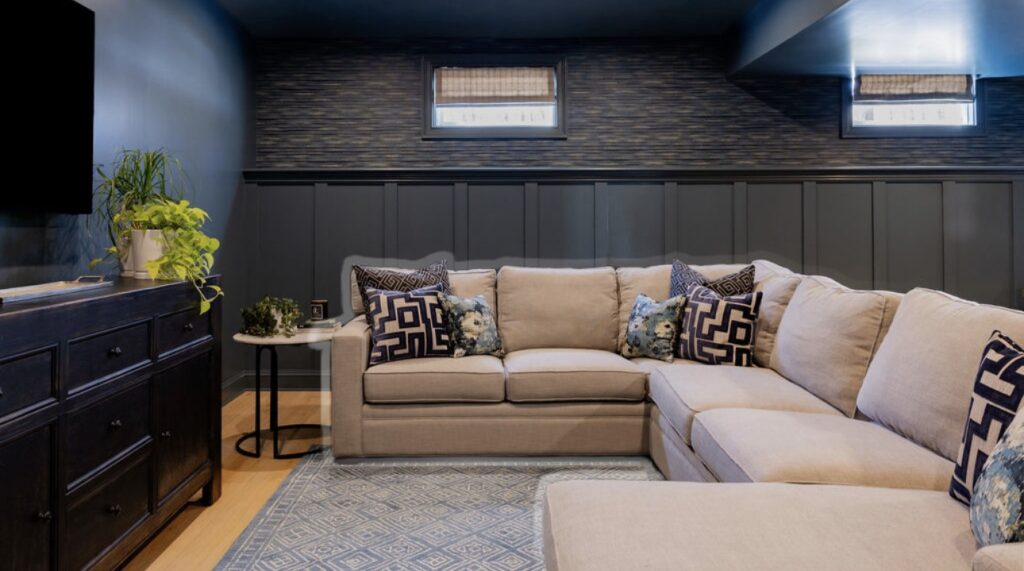 Moody basement lounge with sectional sofa and dark paneling in Ridgefield CT by Beck Haus